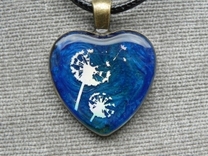 Halskette mit Medaillon in Herzform, silberne Pusteblume auf blauem Untergrund