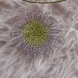 Wundervoller Blütenanhänger in den Farben grün und lila aus gestricktem Kupferlackdraht