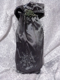 Geschenkverpackung für die Flasche  genäht aus Satinstoff grau mit silbernen Sternen und einer Brosche verziert