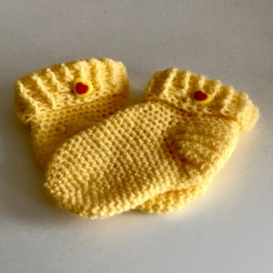Schöne von Hand gehäkelte Socken für ein Kleinkind in gelb mit Knopf