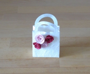 Geschenkverpackung - kleines Täschchen aus weißem Maulbeerbaumpapier mit vier Miniröschen in Rot und Rosa
