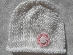 Mütze für Neugeborene Babys mit Rollrand und aufgenähtem rosa Blümchen in weiß aus reiner Baumwolle handgestrickt - Handarbeit kaufen