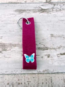 magenta farbener Schlüsselanhänger bestickt mit einem Schmetterling