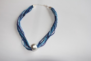 Halskette aus Seidenschnüre in verschiedenen Blautönen und türkis mit einer silberfarbenen Kugel