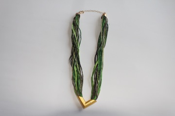 Halskette aus Seidenschnüre in verschiedenen Grüntönen, braun und taupe mit einem vergoldeten Schmuckstück in V-Form mit kleinem Glitzerstein.